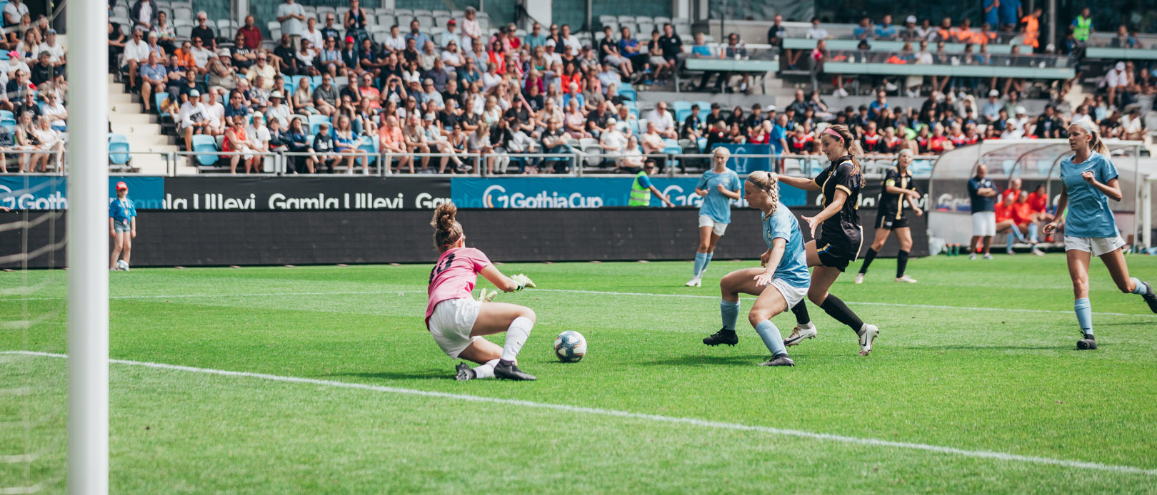 En målvakt slänger sig för att hindra att en fotboll hamnar i mål. I bakgrunden syns Gamla Ullevis läktare som är fulla.