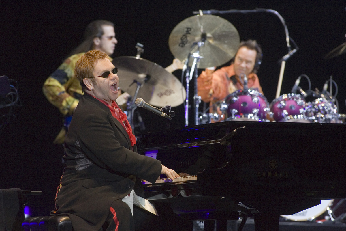 Elton John sjunger vid ett piano.