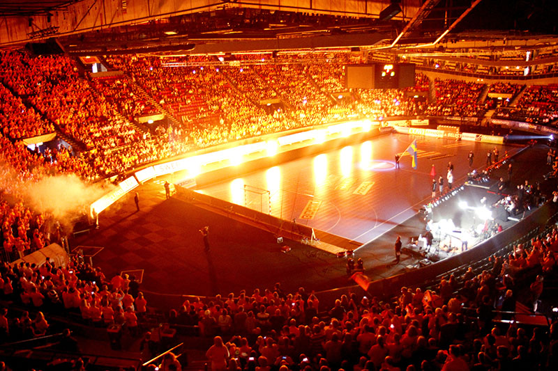 Orange ljus över Scandinaviums läktare under SM-final i handboll.