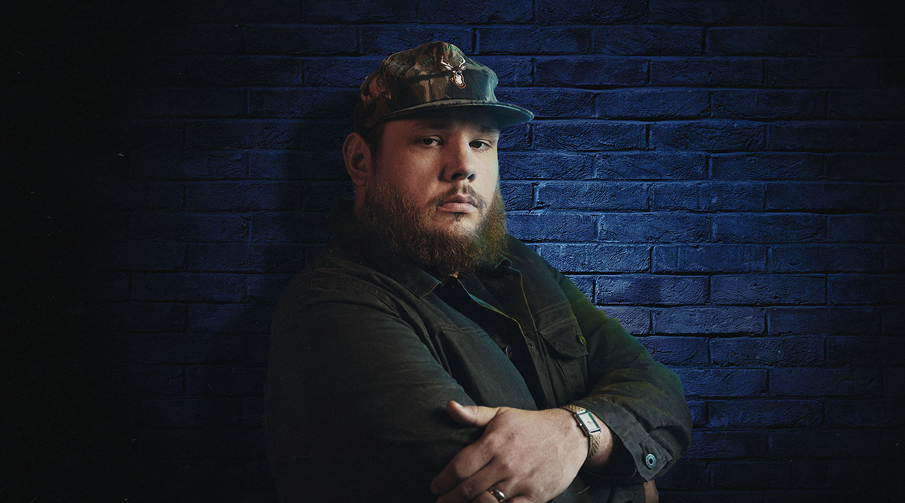 Luke Combs lutar mot en blå vägg.