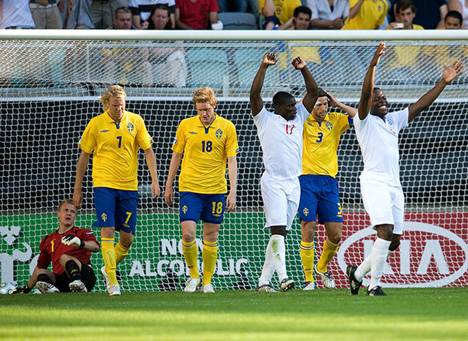 Två av Englands spelare firar med händerna i luften. Bakom går tre besvikna spelare från det svenska laget.