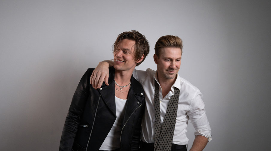 Viktor Norén och Linus Wahlgren håller om varandra mot en grå bakgrund. 