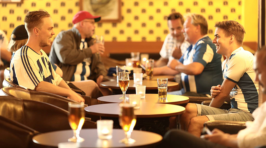 Två supportrar som sitter och dricker öl på John Scotts Gamla Ullevi.